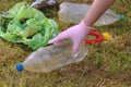 Woman girl in glove saving the planet earth nature and environment from pollution of plastic. Taking bottle from the grand green Royalty Free Stock Photo