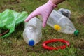 Woman girl in glove saving the planet earth nature and environment from pollution of plastic. Taking bottle from the grand green Royalty Free Stock Photo