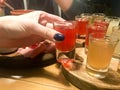 Woman, girl holds in her hand with a manicure on her fingers a delicious red glass, a shot with strong alcohol, vodka, brandy Royalty Free Stock Photo