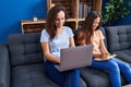 Woman and girl mother and daughter using laptop write on notebook at home Royalty Free Stock Photo