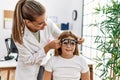 Woman and girl oculist and patient examining vision using optometrist glasses at clinic Royalty Free Stock Photo