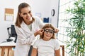 Woman and girl oculist and patient examining vision using optometrist glasses at clinic Royalty Free Stock Photo