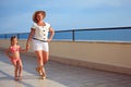 Woman and girl walk on veranda near seacoast