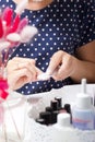 A woman gives herself a manicure. Removes old nail Polish with a nail buff. Next to a set of lacquers, tools and a bouquet of Royalty Free Stock Photo