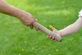 Woman giving the relay baton into a child`s hand