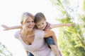 Woman giving young girl piggyback ride smiling