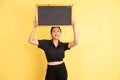 woman glancing up standing holding blackboard above head