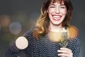 Woman with a glass of champagne on dark background,flares and bokeh. Lady with long curly hair and ref lips celebrating and laughi