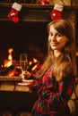 Woman with a glass of champagne by the fireplace. Young woman si Royalty Free Stock Photo