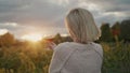 A woman with a glass of red wine in her hand stands against the background of a vineyard where the sun sets beautifully Royalty Free Stock Photo