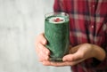 Woman with glass of spirulina smoothie, closeup