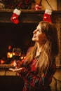 Woman with a glass of wine by the fireplace. Young attractive wo