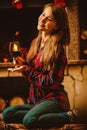 Woman with a glass of wine by the fireplace. Young attractive wo