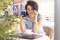 Woman in glass working remotely with laptop and phone in cafe. Beautiful brunette using notebook in cafe. Royalty Free Stock Photo