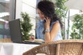 Woman in glass working remotely with laptop and phone in cafe. Beautiful brunette using notebook in cafe Royalty Free Stock Photo