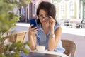 Woman in glass working remotely with laptop and phone in cafe. Beautiful brunette using notebook in cafe. Happy businesswoman Royalty Free Stock Photo