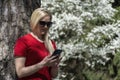 A woman in glasses with blonde hair looking at the phone on a sunny day Royalty Free Stock Photo