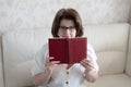 Woman with glasses with a book sitting on the sofa Royalty Free Stock Photo