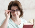 Woman with glasses with a book sitting on the sofa Royalty Free Stock Photo