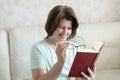 Woman with glasses with a book sitting on the sofa Royalty Free Stock Photo