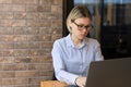 A woman with glasses is doing business in the office on a laptop. Royalty Free Stock Photo