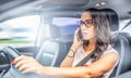 Woman in glasses driving a car calls on a cell phone, holding steering wheel with only one hand Royalty Free Stock Photo