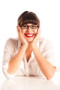 Woman in glasses with elbows on desk, smiling