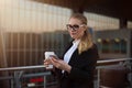 Woman in glasses and formal wear intelligent government worker reading news in internet via mobile phone Royalty Free Stock Photo