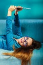 Woman in glasses laying on sofa with pc tablet. Royalty Free Stock Photo