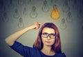 Woman in glasses looking up with light idea bulb above head