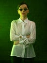 Woman with glasses in neon green lighting.