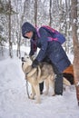 Woman in glasses posing with husky dog in snowy forest