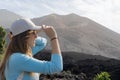 woman with glasses puts on her cap in front of the tajogaite volcano