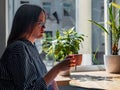 Woman in glasses sitting by wood table in coffee shop, holding cup and drinking. Sad tired female in cafeteria thinking Royalty Free Stock Photo