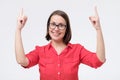 Woman in glasses smiling pointing up showing copy space. Royalty Free Stock Photo