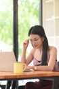 A woman with glasses is using a computer laptop while sitting at the wooden working desk Royalty Free Stock Photo