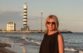 Woman with glasses who is photographed on the beach with a lighthouse behind her for navigators. photo taken on the beaches betwe
