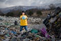 Woman with globe standing on landfill, environmental concept.