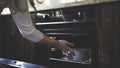 In the kitchen a woman puts a container into an oven