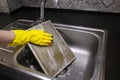 Woman gloved hands cleaning clogged range hood filter in sink Royalty Free Stock Photo