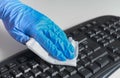 Woman with gloves cleaning and disinfecting computer keyboard with napkins Corona virus cleaning and disinfection of your