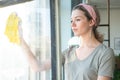 Woman in gloves cleaning window with rag and cleanser spray at home. housework and housekeeping concept