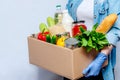 Woman in Gloves Holding Donation Box Food Supplies for People in Isolation on Yellow Background. Royalty Free Stock Photo