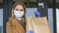 Woman in gloves and mask with bags of groceries on the background of entering the grocery store