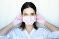 A woman in gloves and a protective mask stands on a light background Royalty Free Stock Photo