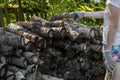 a woman in gloves stacks firewood on a pallet