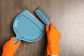 Woman in gloves sweeping wooden floor with plastic whisk broom and dustpan, top view Royalty Free Stock Photo