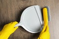 Woman in gloves sweeping wooden floor with plastic whisk broom and dustpan, top view Royalty Free Stock Photo