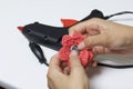 A woman glues a metal hairpin to a knitted brooch in the form of a flower.