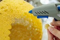 Woman glues pasta with a hot glue gun during the manufacture of crafts